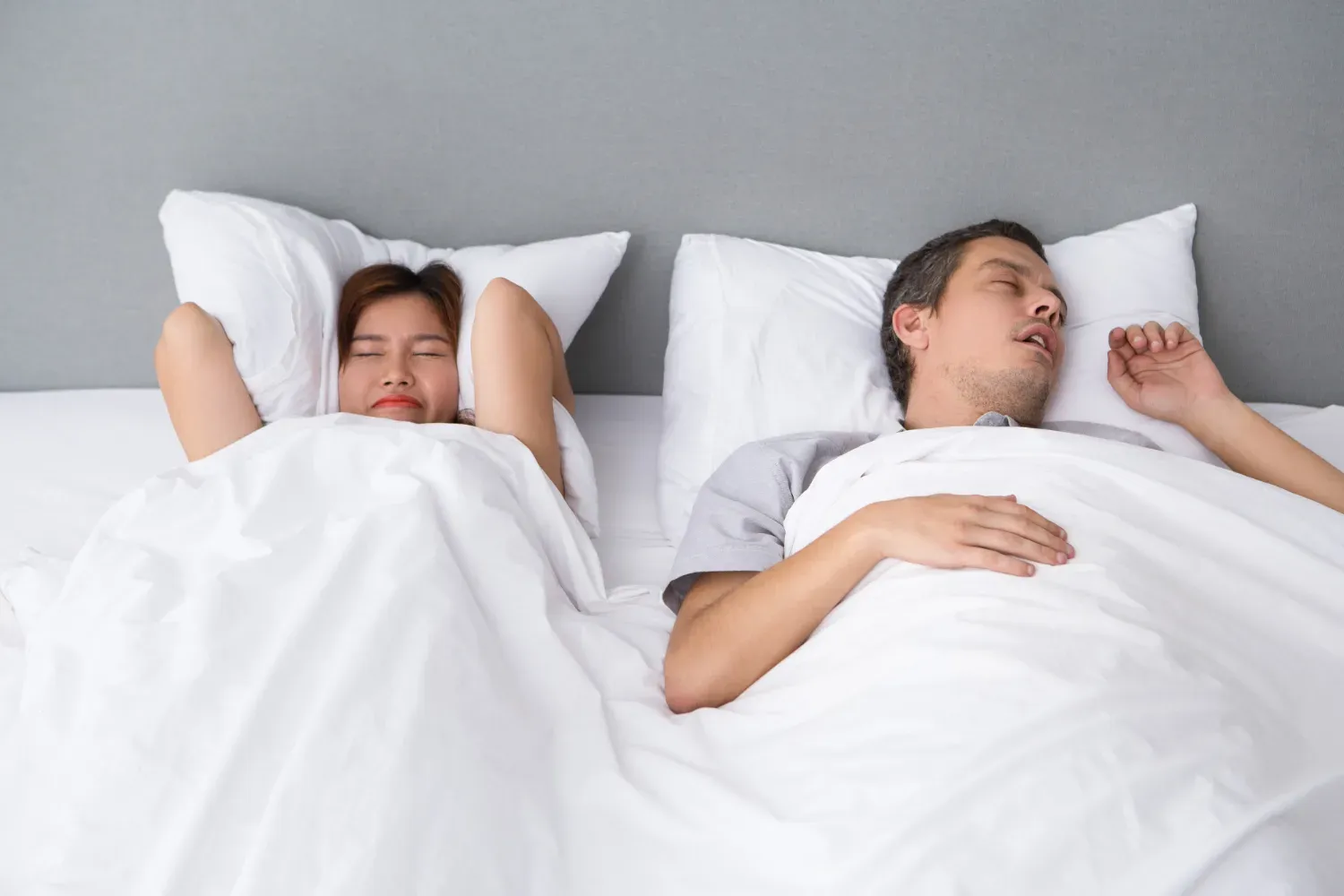 man snoring loudly, disturbing his partner's sleep