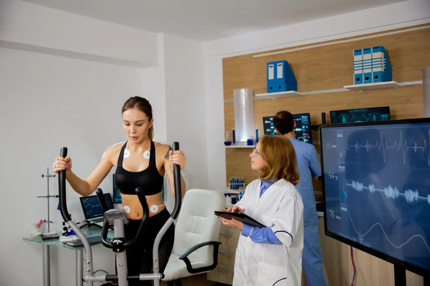patient walking on a treadmill during a stress test, with medical equipment monitoring heart activity in a clinical setting